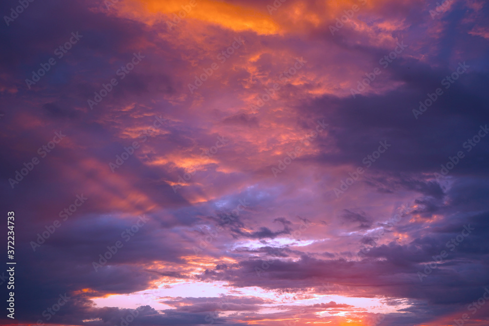 Sunset in the clouds. Blue orange purple sunset background. A bright beautiful sunset on a dramatic sky. Cloudscape. Evening thunderstorm.