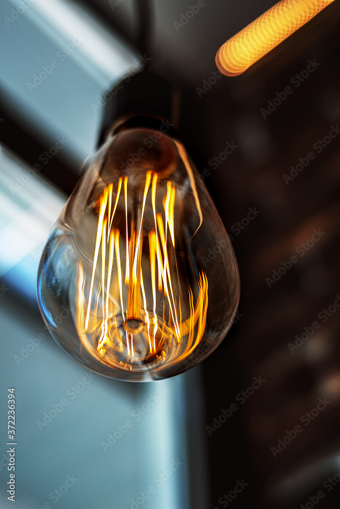 Vintage style light bulb hanging from the ceiling. Decorative lights at home. Old Edison bulb.