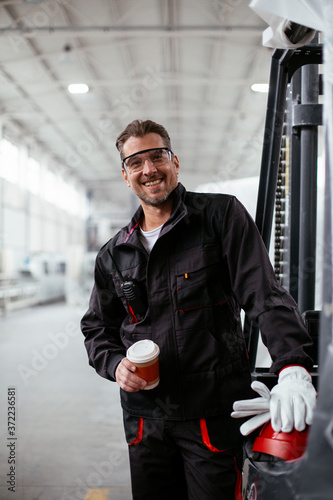 Portrait of worker in factory. Hadnsome man drinking coffee in factory. photo