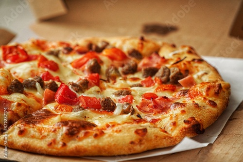 Thin crust Pizza, close up photo of a delicious pizza with mozzarella cheese, onions, meat, tomato.