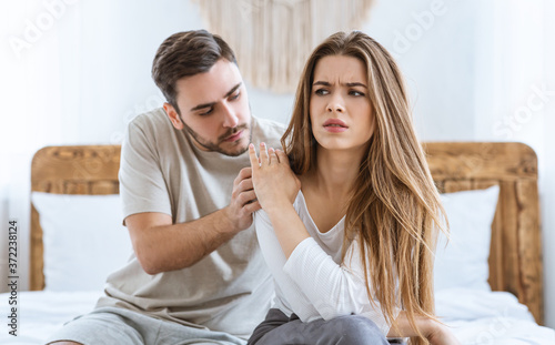 Relationship problems. Husband calms his wife, upset woman rejects boy on bed