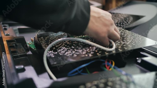 Worker assembles traffic light microcircuits at the production site. Close-up. LED matrix, light block, energy-saving traffic lights, electronics. Repair and assembly of traffic lights.