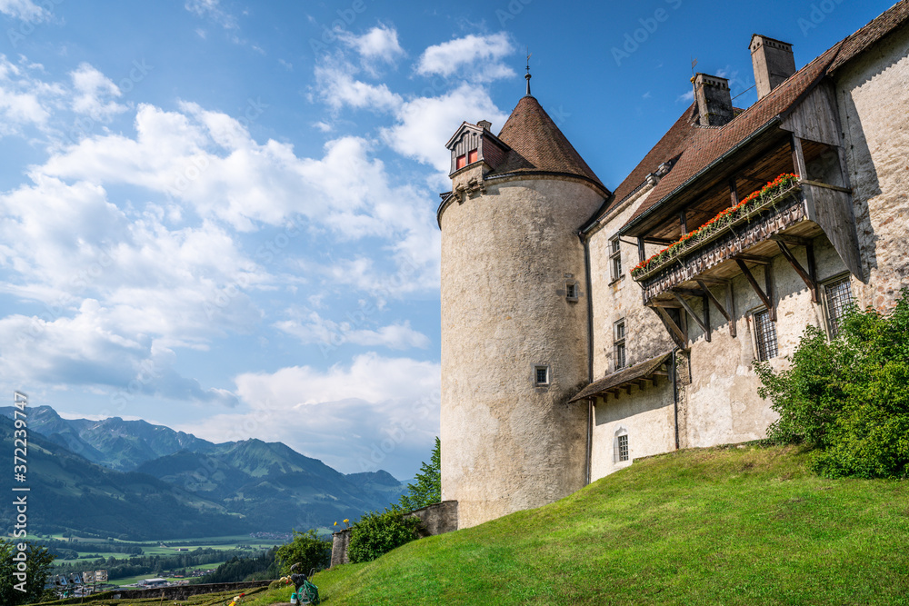 Gruyeres medieval castle details view with balcony tower and garden and mountains in background in La Gruyere Switzerland