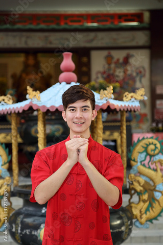 Young south east asian Chinese man traditional costume hand gesture greeting thanks welcome outdoors at temple © oqba