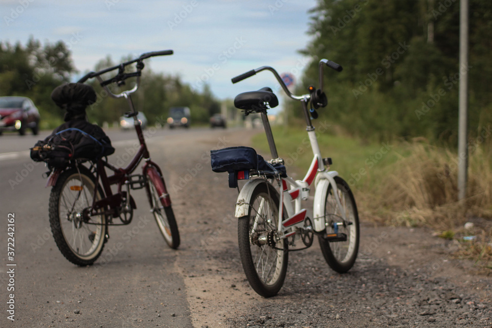 Fototapeta premium Two bicycles standing on an asphalt road in summer