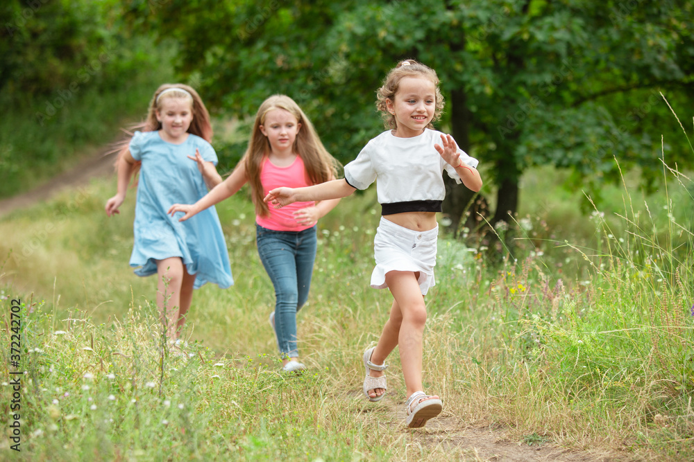 Memories. Kids, children running on green forest. Cheerful and happy boys and girs playing, laughting, running through green blooming meadow. Childhood and summertime, sincere emotions concept.