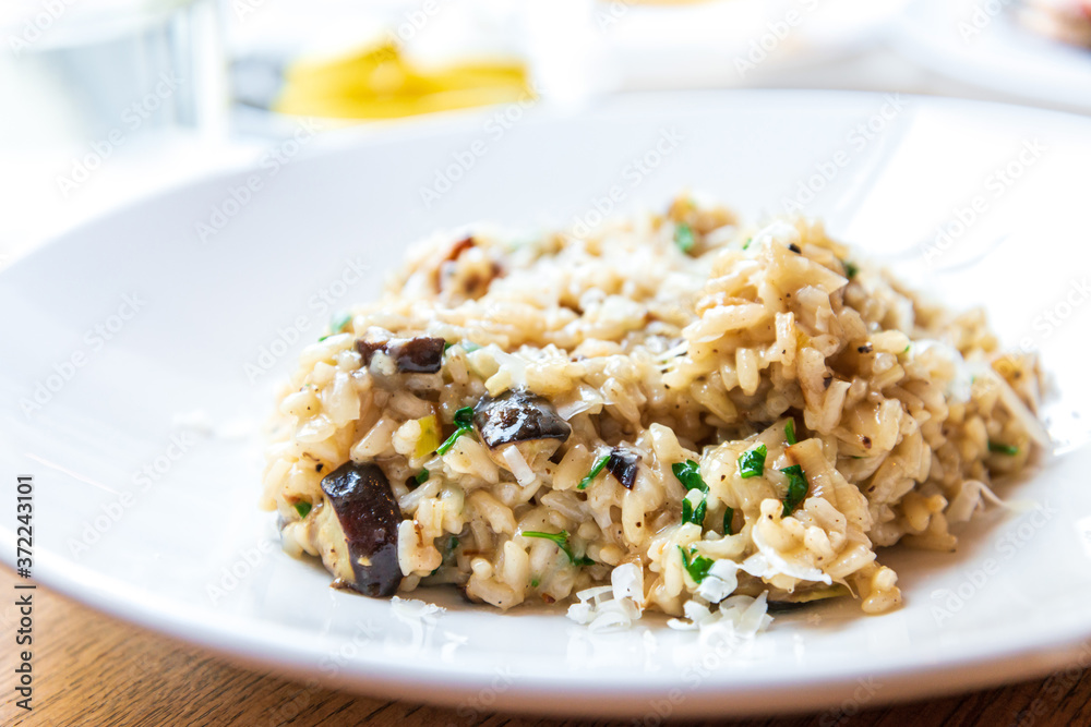 Delicious Italian vegetarian risotto cooked with mushrooms and onions served in white plate. Delicious Italian vegetarian risotto cooked with mushrooms and onions served in white plate.