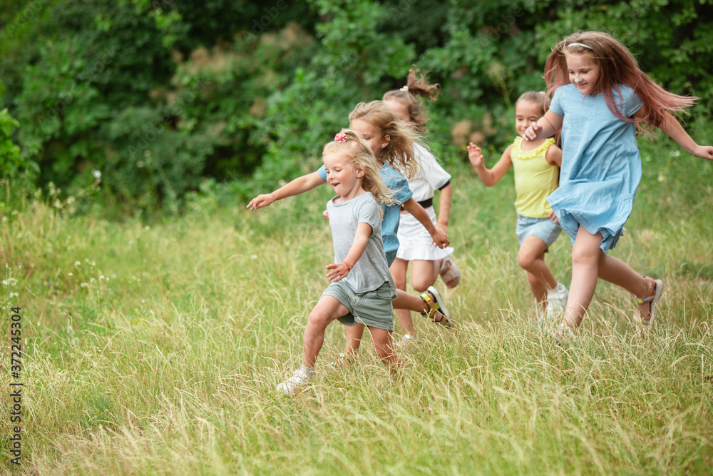 Angels. Kids, children running on green forest. Cheerful and happy boys and girs playing, laughting, running through green blooming meadow. Childhood and summertime, sincere emotions concept. Angels. Kids, children running on green forest. Cheerful and happy boys and girs playing, laughting, running through green blooming meadow. Childhood and summertime, sincere emotions concept.