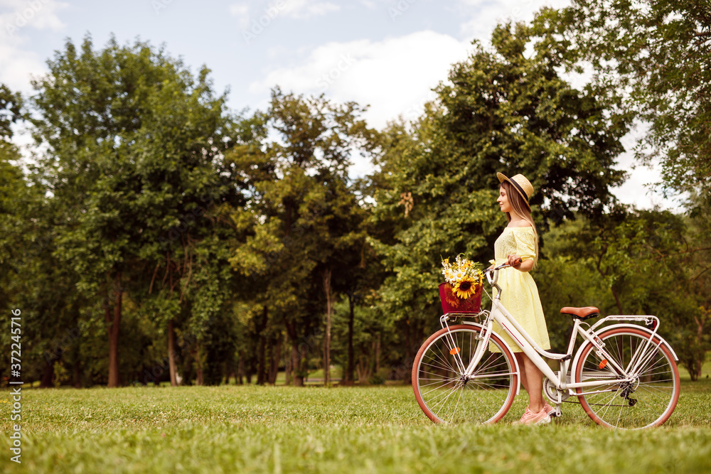 Obraz premium Young woman with bicycle in meadow