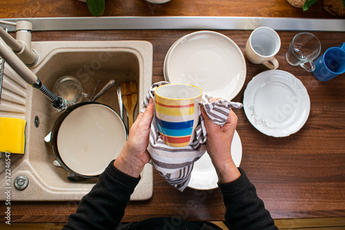Obraz na plátně Woman wiping dishware with cotton towel in kitchen