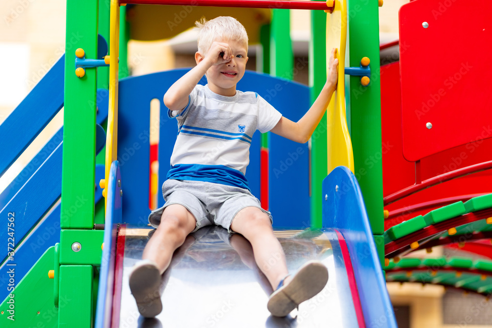 Obraz premium happy baby boy 5-6 years old playing on the Playground in the yard in the summer. Children's lifestyle