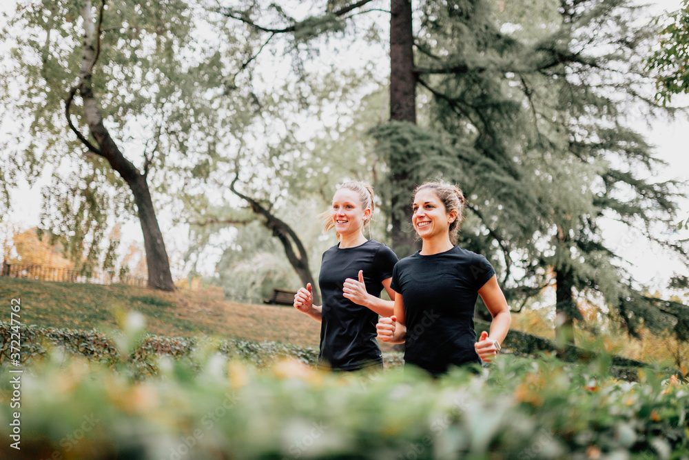 A couple of women running outside trought the park A couple of women running outside trought the park