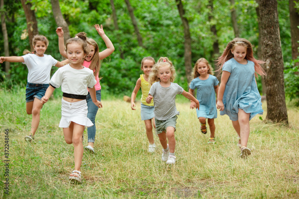 Obraz premium Wspomnienia. Dzieci, dzieci biegające po zielonym lesie. Wesoły i wesoły chłopcy i dziewczęta bawią się, śmieją, biegają po zielonej kwitnącej łące. Dzieciństwo i lato, koncepcja szczerych emocji.