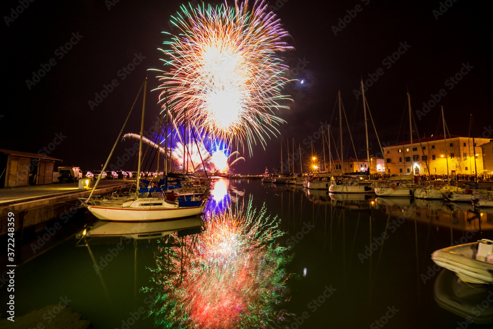 Tuscany Maremma Castiglione della Pescaia, fireworks over the sea, panoramic night view of the port and the castle