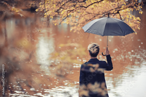 Fototapeta Naklejka Na Ścianę i Meble -  Autumn rainy weather and a young man with an umbrella