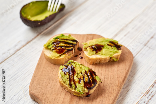 Baguette, bruschetta, canapes with avocado and maple syrup on a light wooden background.