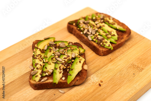 Toast with sliced avocado, mixture of seeds on a wooden background. Healthy snack tomorrow. The concept of proper nutrition, diet.