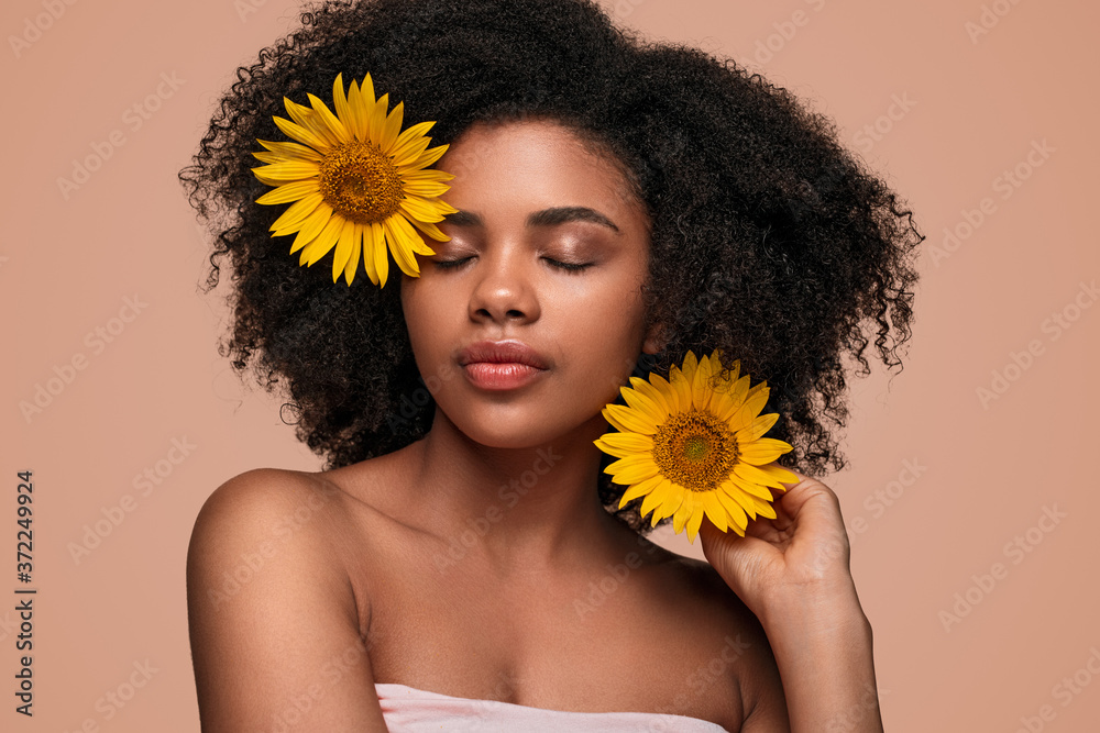 Black female model decorating hair with flowers