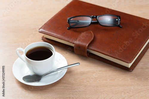 Brown leather notebook and glasses on table