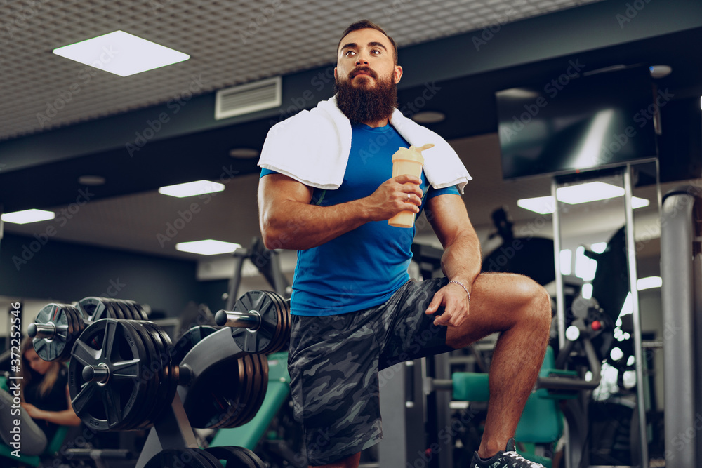 Bearded young man bodybuilder in blue t-shirt standing in gym Bearded young man bodybuilder in blue t-shirt standing in gym
