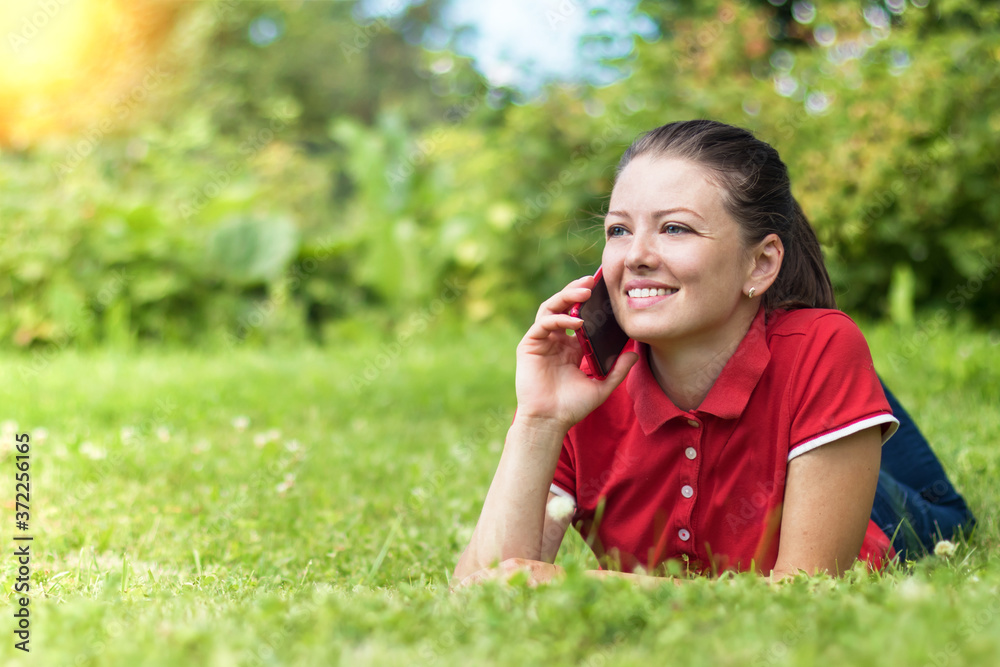happy young woman in the park smiling and talking on smartphone. beautiful girl get a good news on her mobile phone. leisure in nature. copy space, place for text happy young woman in the park smiling and talking on smartphone. beautiful girl get a good news on her mobile phone. leisure in nature. copy space, place for text