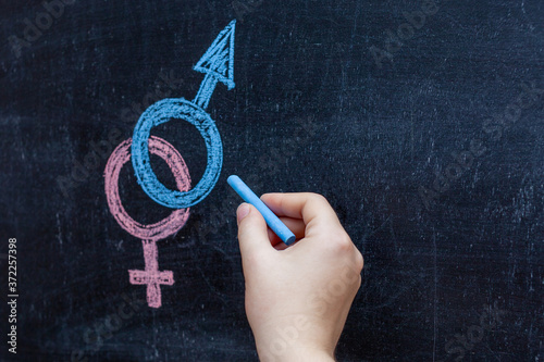 Man equal to woman gender equality concept on black chalkboard with woman hand holding chalk