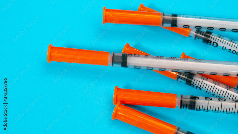 Insulin vial and syringe on blue background. Health care, doctor, clinic or hospital, medical concept. World diabetes day. Ready for vaccine injection. Pain treatment, illegal use, vaccination Insulin vial and syringe on blue background. Health care, doctor, clinic or hospital, medical concept. World diabetes day. Ready for vaccine injection. Pain treatment, illegal use, vaccination
