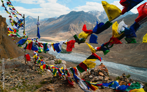 Prayer flags blow in the wind over Spiti river and Himalayas. Kaza, Himachal Pradesh, India.