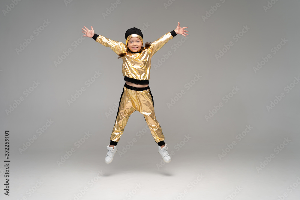 Fototapeta premium Happy little girl in gold suit dancing isolated on white background