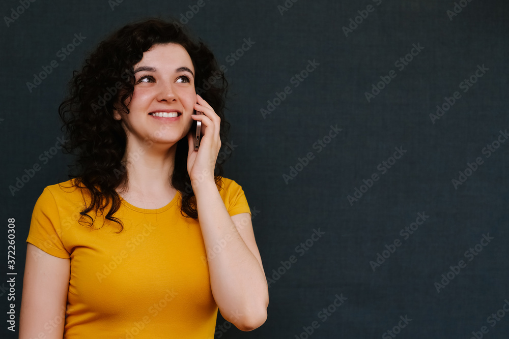 Young charismatic caucasian woman with curly dark hair on the grey background. Young charismatic caucasian woman with curly dark hair on the grey background.