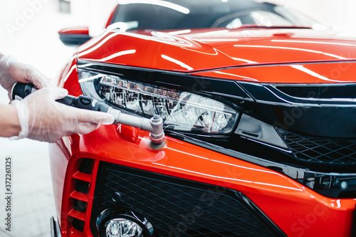 Car detailing - Worker with orbital polisher in auto repair shop.  photo