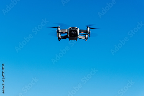 Fototapeta Naklejka Na Ścianę i Meble -  Dron flying over a blue sky background while being held by gps. Equipped with camera and video action.