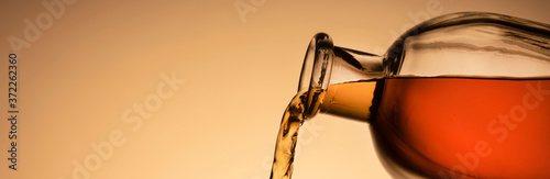 a bottle of whiskey, Bourbon, or liqueur. pouring liquid, a stream from the neck. close - up orange background. panoramic photo, copy space