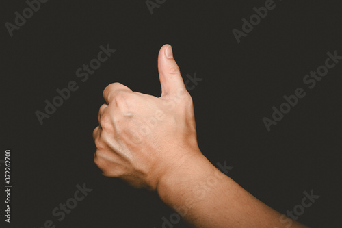 The man's hand that thumbs up is a symbol of good on black background.