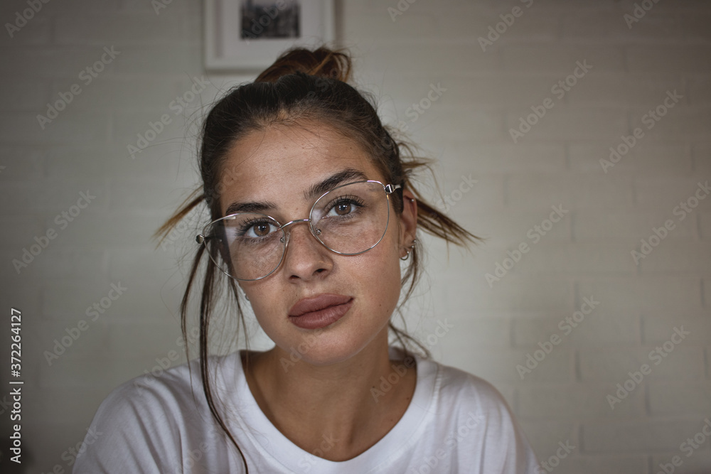 Fototapeta premium Close up portrait of young beautiful girl with reading glasses looking at the camera