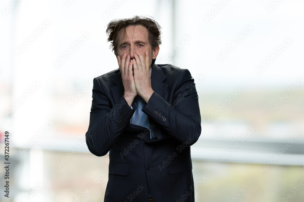 Shocked desperate businessman covering his face. Stressed overhelmed man on blurred background. It is a fail. Nervous breakdown. Shocked desperate businessman covering his face. Stressed overhelmed man on blurred background. It is a fail. Nervous breakdown.
