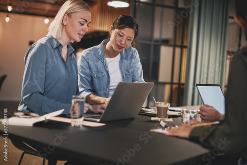 Two businesswomen working on a laptop during an office meeting