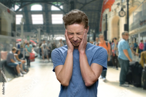Stressed teenage boy suffering from headache. Airport blurrred background interior.