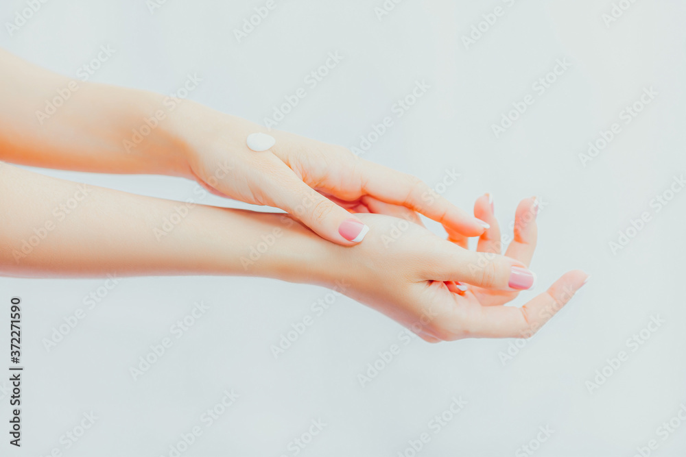 Naklejka premium Woman with french manicure applies cream to her hands