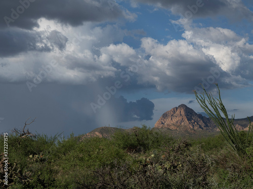 A desert monsoon storm near a prominent rock formation