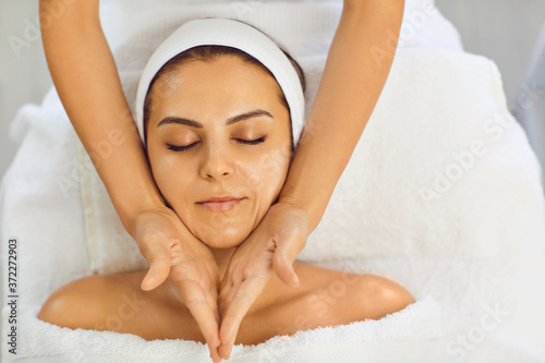 Young woman receiving facial massage at the salon kosmetalogicheskom. Facial skin care.