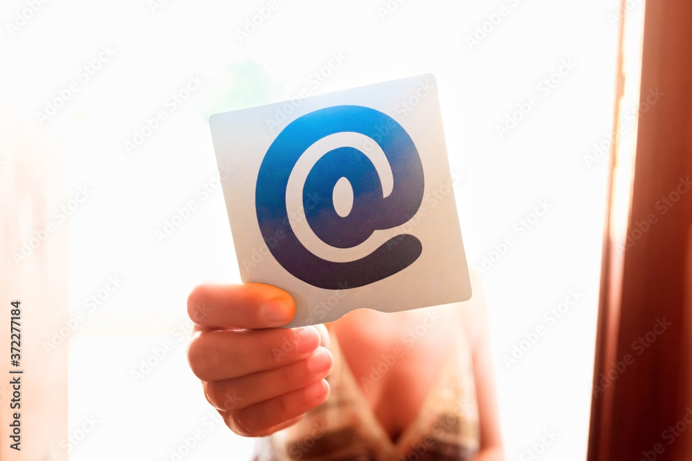 Person holding the at symbol between his fingers Person holding the at symbol between his fingers