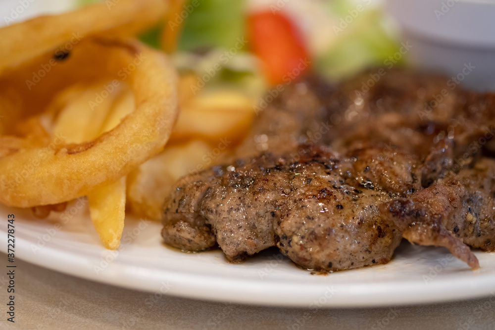 Pork steak with black pepper sauce, salad and French fries