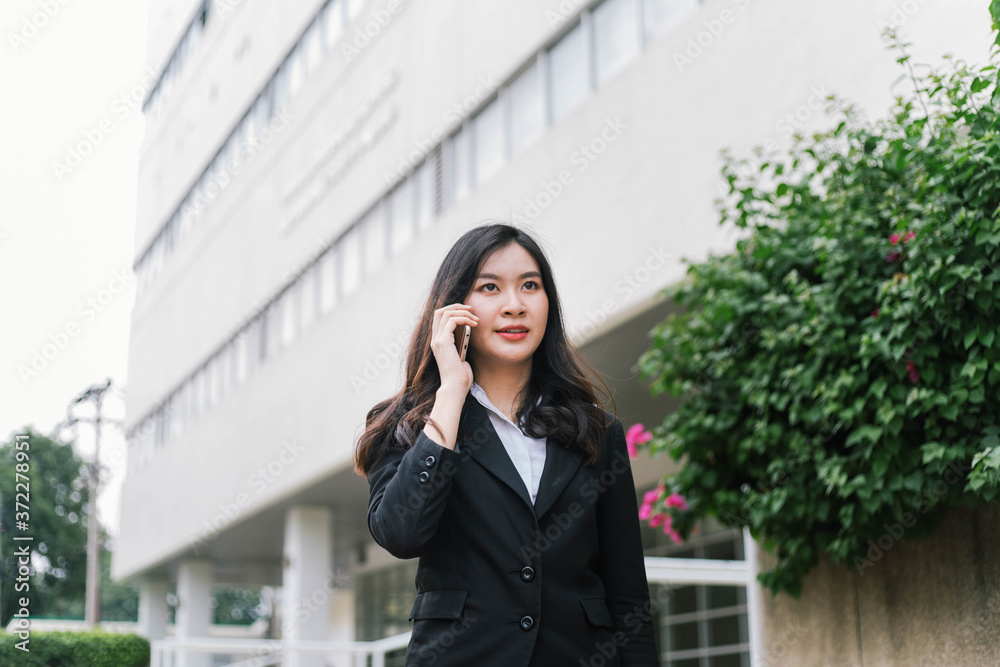 Beautiful asian business woman talking on cellphone while walking outdoor Beautiful asian business woman talking on cellphone while walking outdoor