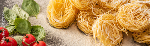 raw Italian Capellini with vegetables and flour on black background, panoramic shot photo