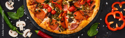 top view of delicious Italian pizza with vegetables and salami on black background, panoramic shot