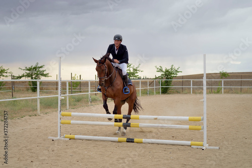 Jockey riding a horse jumping an obstacle on the track. Jumping sport. © fuen30