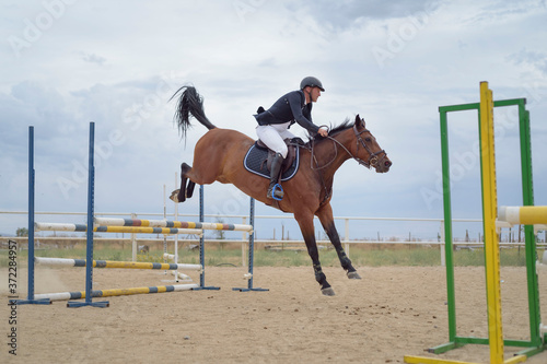 Jockey riding a horse jumping an obstacle on the track. Jumping sport.