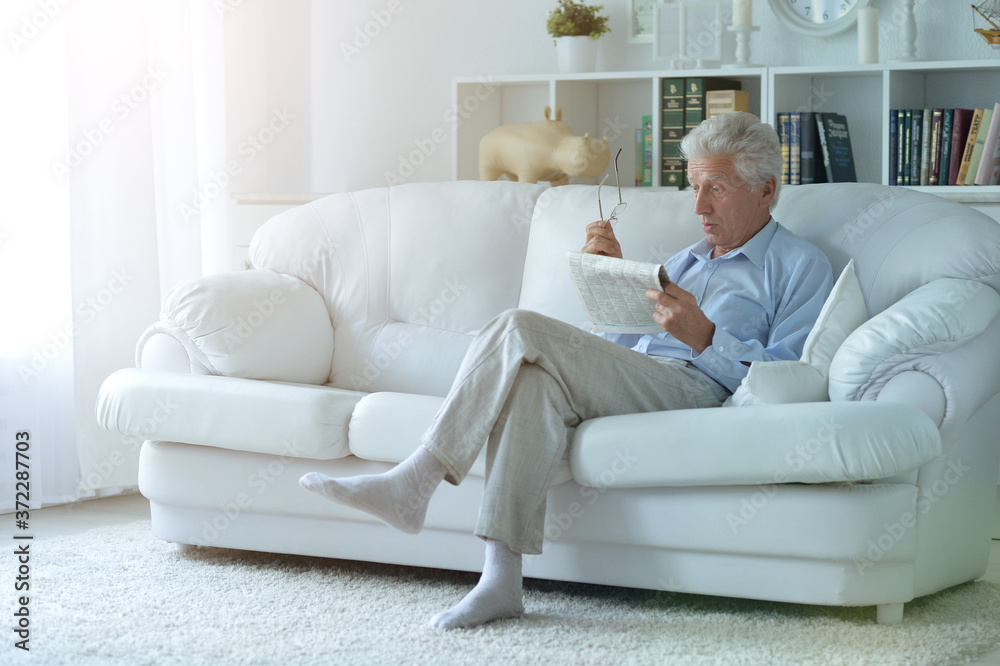 Portrait of senior man reading newspaper at home Portrait of senior man reading newspaper at home