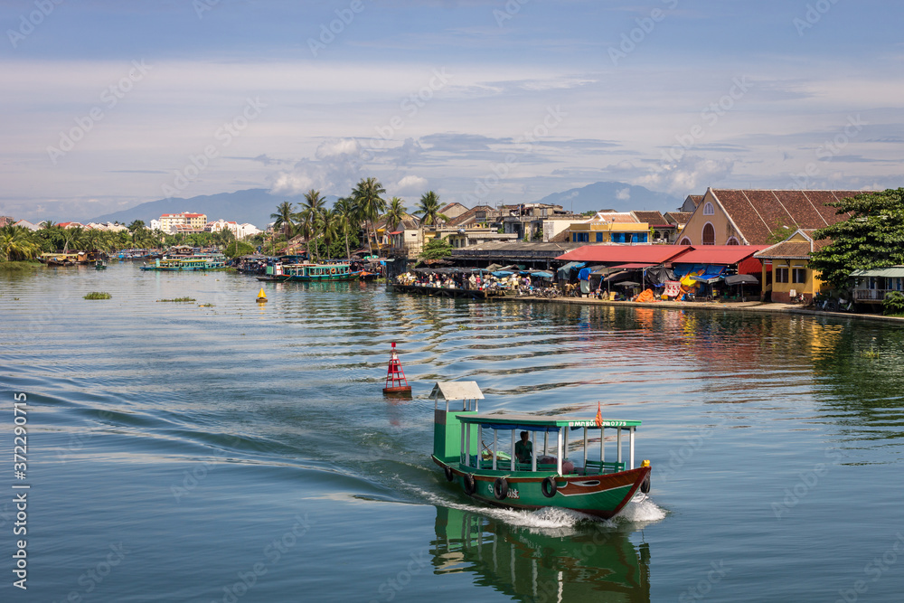 Thu bon river and boat in citycentre of Hoi An, Vietnam, mountain background